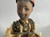 a doll that is sitting on a chair with a hat on