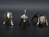 three silver elephants are standing in a row on a black surface