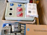 Des cartons contenant du matériel électrique sont empilés les uns sur les autres dans un entrepôt.