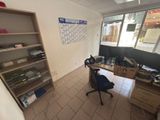 a desk with a computer and a book shelf in the corner