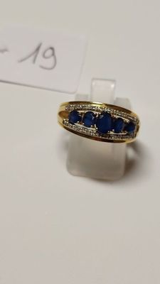 an image of a gold ring with blue stones on a white surface