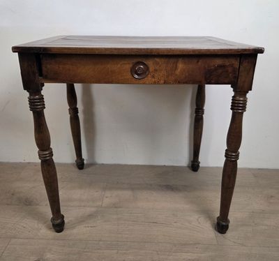une vieille table en bois avec un tiroir en dessous, posée sur un parquet en bois massif
