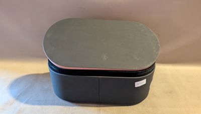 un gros plan d'une boîte noire avec un couvercle rose posée sur une table
