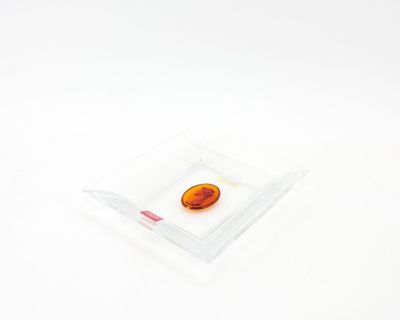 une pierre orange dans un bol en verre transparent posé sur une surface blanche