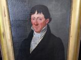 tableau représentant un homme vêtu d'un manteau noir et d'une chemise blanche, dans un cadre doré