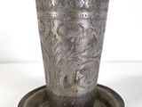 a silver cup sitting on a saucer on a plate