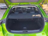 the back of a green car with its trunk open in a parking lot