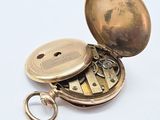 a gold pocket watch with a key on a white surface