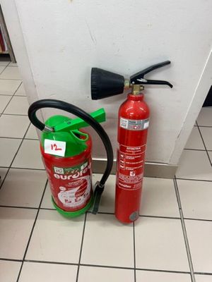un extincteur posé à côté d'une borne d'incendie, au sol