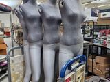 trois mannequins assis sur un chariot dans un magasin