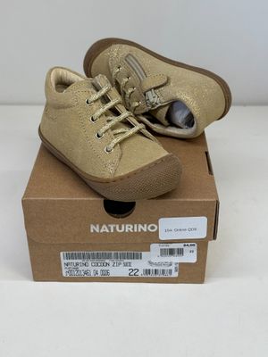 des chaussures de petit garçon dans une boîte posée sur une surface blanche