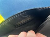 a person holding a black purse with a yellow handle