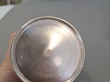 a person holding a silver cup on a table