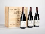 trois bouteilles de vin devant une caisse en bois