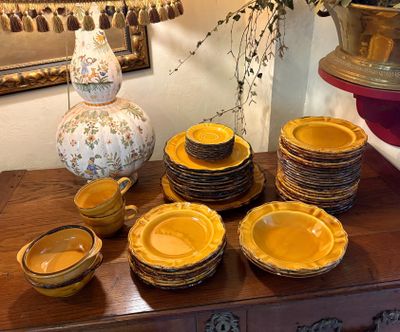 de nombreuses assiettes et bols posés sur une table, avec un vase en arrière-plan