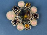 sterling silver and glass broochle with pearls on a blue surface
