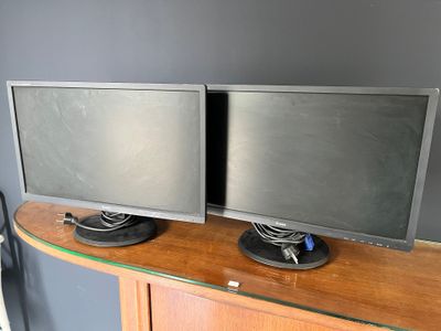 two monitors sitting on top of a wooden desk