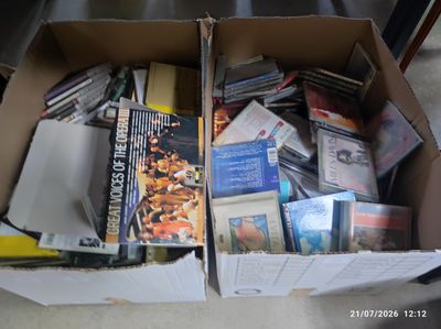 une boîte en carton remplie de livres et de DVD posée par terre