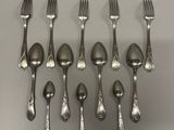 six fourchettes et cuillères sont disposées en rangée sur une table