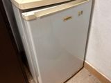 a small refrigerator with a microwave on top of it