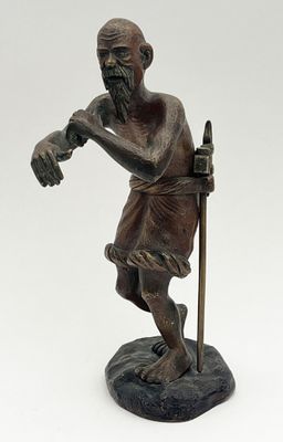 une vieille statue en bronze représentant un homme muni d'une canne