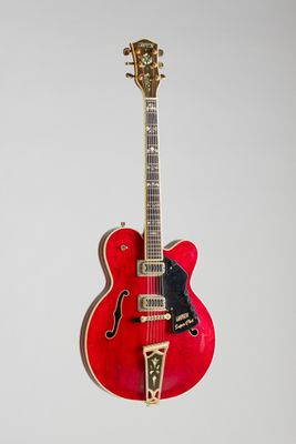 une guitare rouge accrochée à un mur sur fond blanc