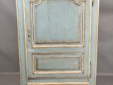 une vieille armoire bleue à deux portes, avec un tiroir en dessous