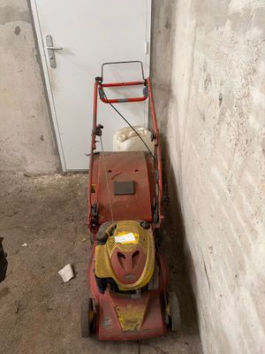 une tondeuse à gazon posée dans un coin d'une pièce