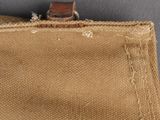 the back of a tan canvas bag with a brown leather handle