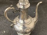 a silver tea pot sitting on a black surface