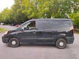 a black van parked in a parking lot with trees in the background