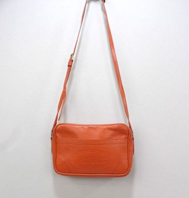 an orange purse hanging on a wall with a white wall behind it