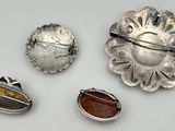 three silver brooches and a silver broochle on a white surface