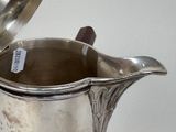 a silver pitcher with a lid on a table
