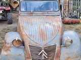 a rusted old car parked under a metal structure