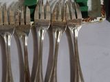several forks and spoons are lined up on a table