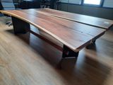 a large wooden table with a black base in the middle of a room