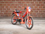 a small red motorcycle parked in front of a brick wall