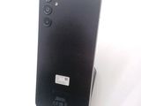 the back of a black cell phone sitting on top of a white surface