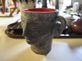 a cup with a face on it sitting on a table
