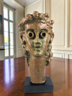 statue représentant la tête d'une femme posée sur une table en bois dans une pièce