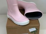 une paire de bottes de pluie roses posée sur une boîte en carton