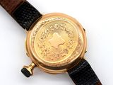a gold watch on a black leather strap on a white surface