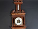 an old wooden clock hanging on the wall with a thermometer on it