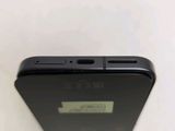 the back of a black cell phone sitting on top of a white table