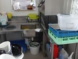 une petite cuisine avec un évier et beaucoup de vaisselle sur le plan de travail