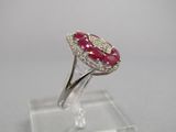 gros plan d'une bague avec une pierre rouge entourée de diamants blancs