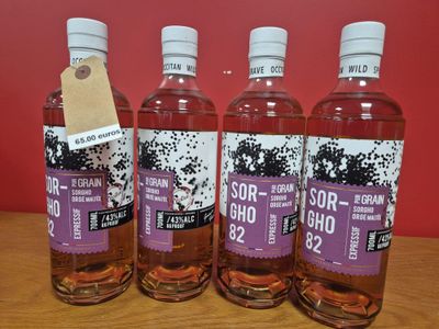 trois bouteilles de vin posées sur une table en bois près d'un mur rouge
