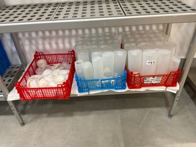 a metal shelf with plastic containers and bottles on it