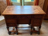 a wooden table with a carved top and drawers on it